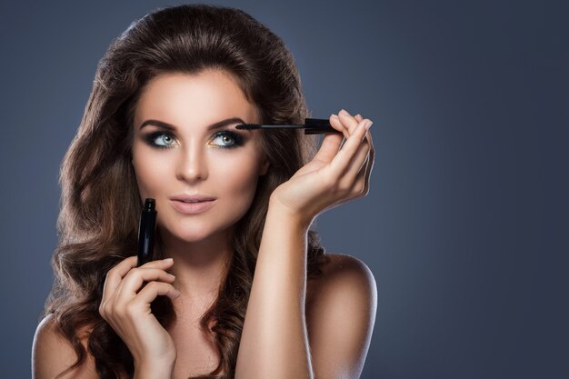 Belle femme appliquant du mascara sur ses cils