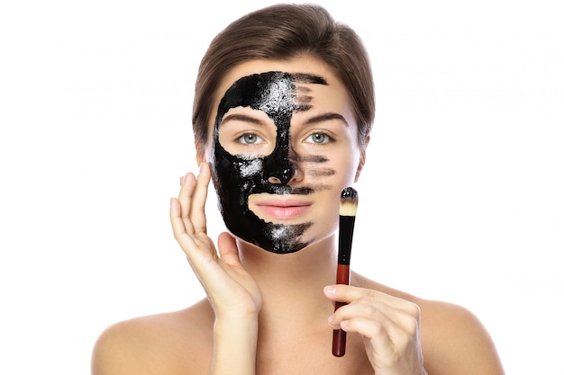 Belle femme applique un masque noir purifiant sur son visage