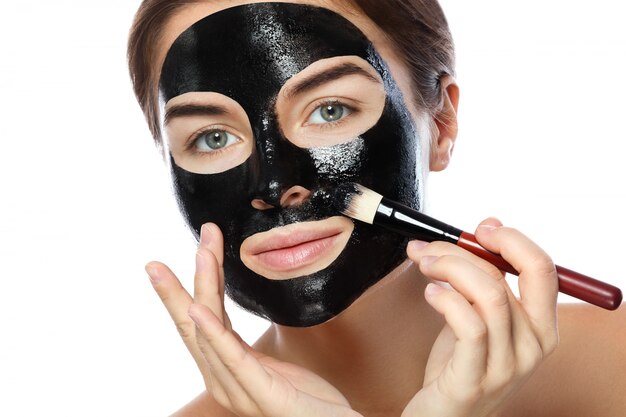 Belle femme applique un masque noir purifiant sur son visage