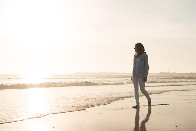 Belle femme appréciant le coucher du soleil à la plage