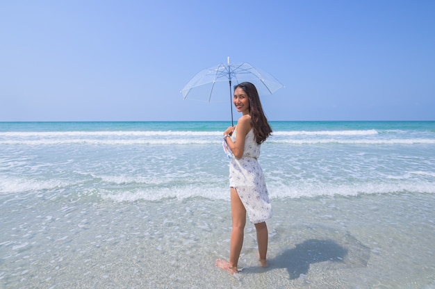 belle femme appréciant la plage avec un parapluie