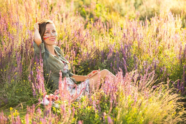 Belle femme artiste assise en train de peindre sur une belle prairie