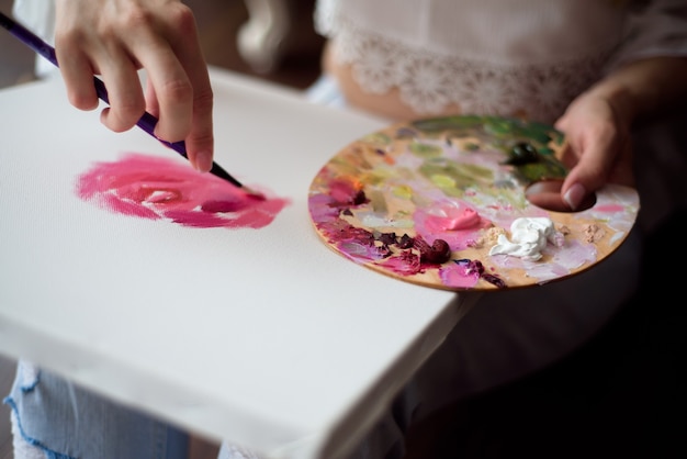 Belle femme artiste dessinant sa photo sur toile avec des couleurs à l'huile à la maison