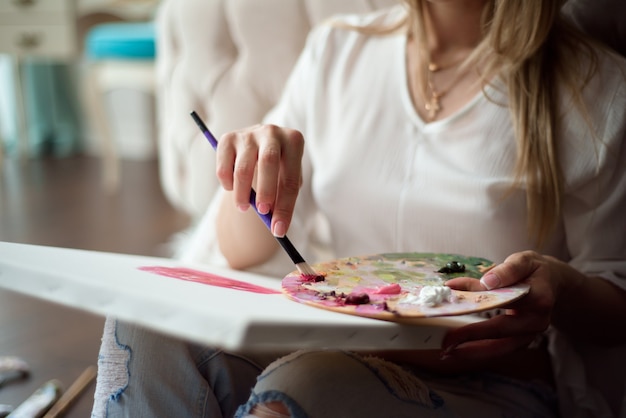 Belle femme artiste dessinant sa photo sur toile avec des couleurs à l'huile à la maison