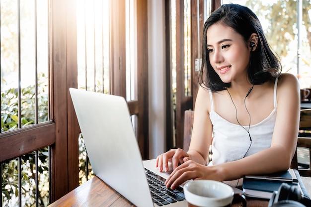 Belle femme asiatique à l&#39;aide d&#39;un ordinateur portable au café.