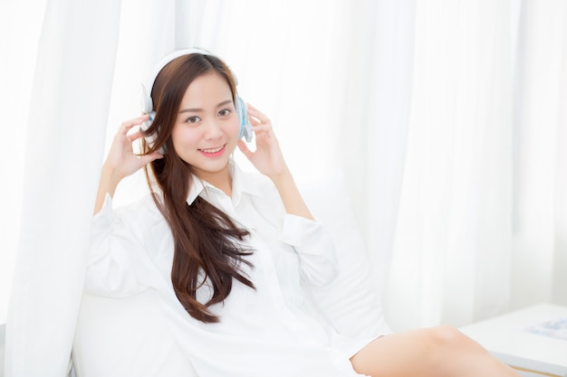 Belle femme asiatique aime écouter de la musique avec un casque tout en restant assis dans la chambre.