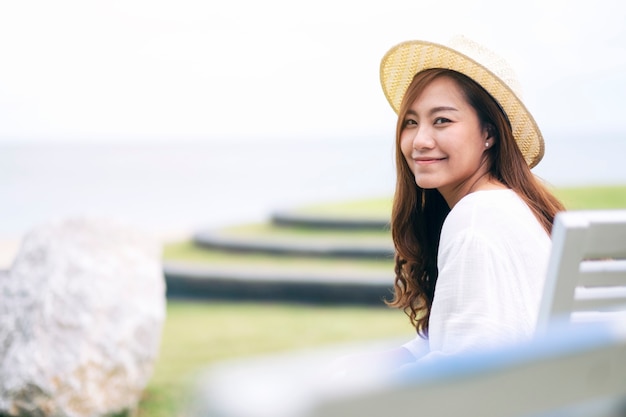 Une belle femme asiatique aime s'asseoir et se détendre sur le banc au bord de la mer