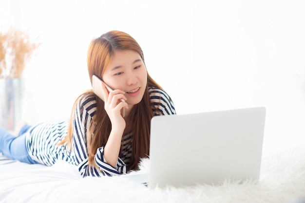 Belle femme asiatique allongée sur le lit à l&#39;aide d&#39;un ordinateur portable