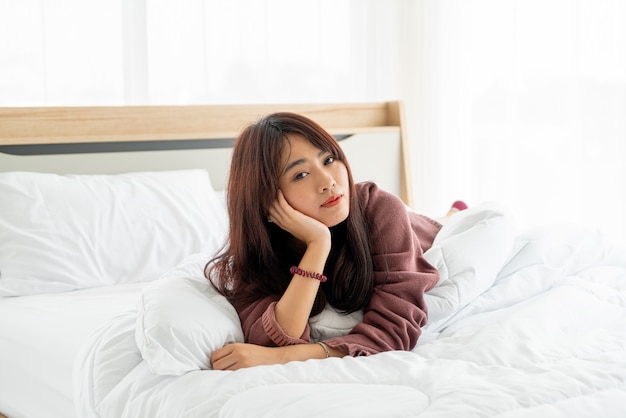 Belle femme asiatique allongée sur le lit le matin