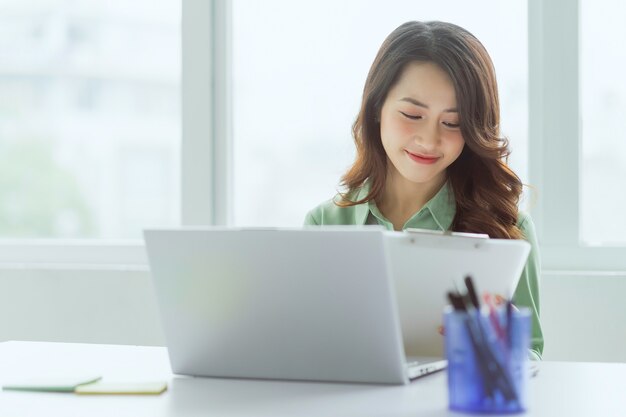 Belle femme asiatique assis travaillant au bureau