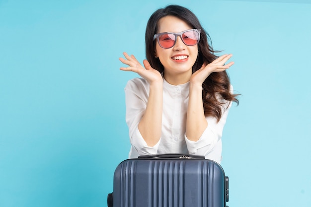 Belle femme asiatique assise posant à côté de la valise et se préparant à voyager