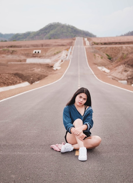 Belle femme asiatique assise sur la route