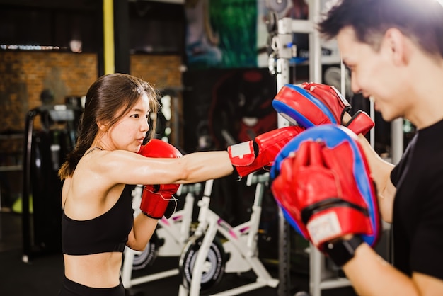 Photo une belle femme asiatique aux cheveux bruns pratiquant la boxe avec un entraîneur masculin asiatique.