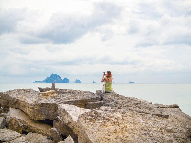 Belle femme asiatique aux cheveux courts à l'aide d'un téléphone intelligent prendre une photo vue paysage marin