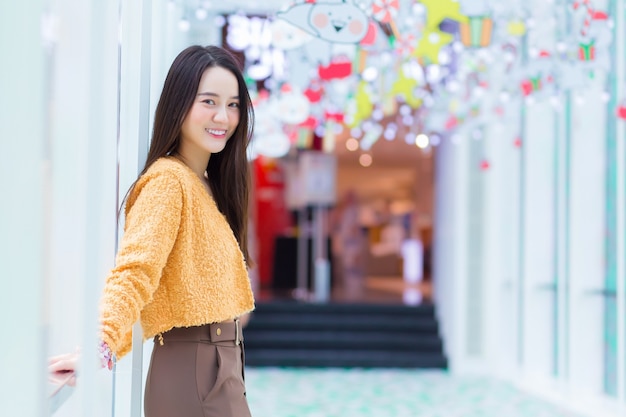 Une belle femme asiatique aux cheveux longs porte un manteau jaune et sourit joyeusement dans le thème pour célébrer