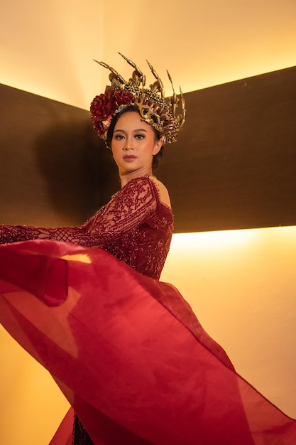 Une belle femme asiatique balance la queue de tissu rouge tout en portant une robe de mariée rouge