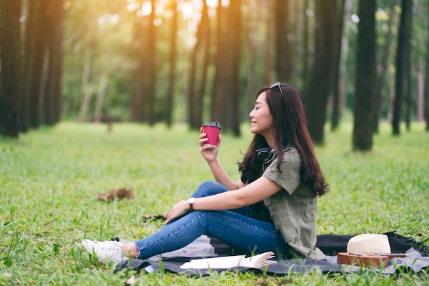 Une belle femme asiatique buvant du café alors qu'elle était assise dans le parc