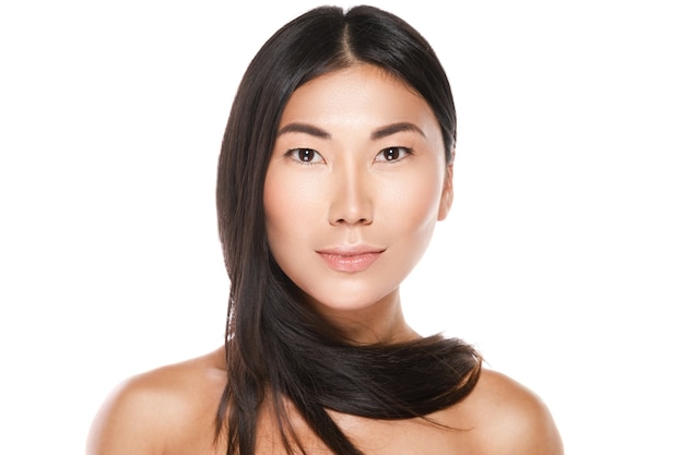 Belle femme asiatique avec des cheveux noirs en bonne santé sur un mur blanc