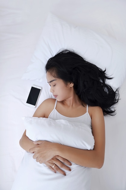 Belle femme asiatique dormir avec téléphone portable