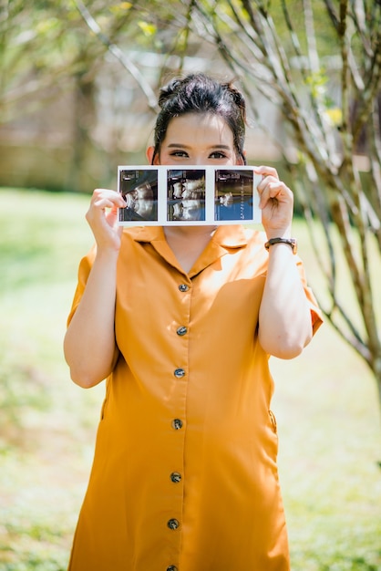 belle femme asiatique enceinte tenant des images d'échographie