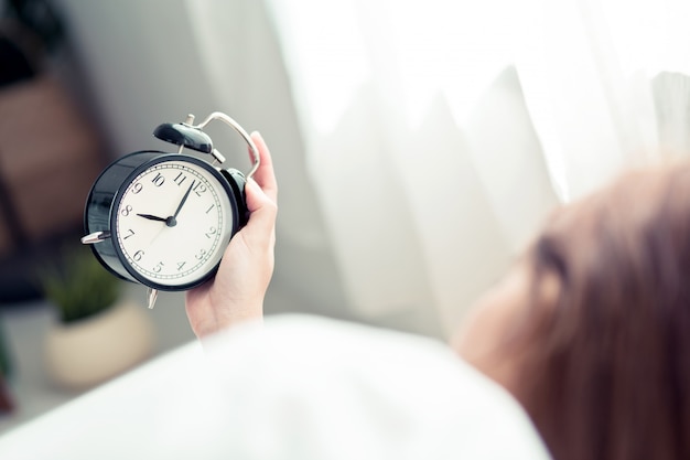 Belle femme asiatique éteindre le réveil le matin.