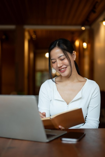 Une belle femme asiatique étudie en ligne ou travaille à distance dans un café