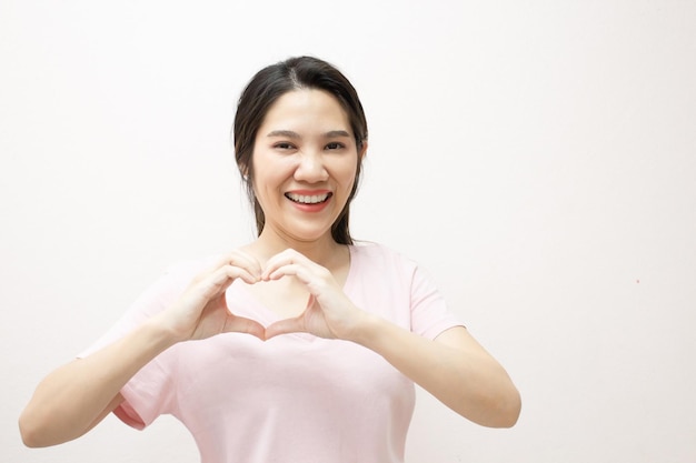 Belle femme asiatique faisant le symbole de forme de coeur à la main devant son visage Un jour de Valentines et amour