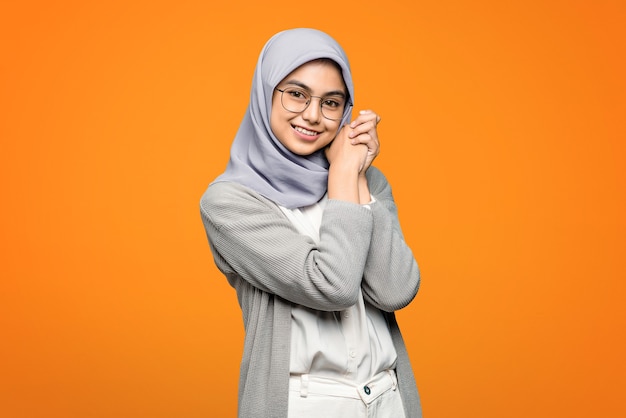 Belle femme asiatique gaie portant des lunettes sur un mur orange