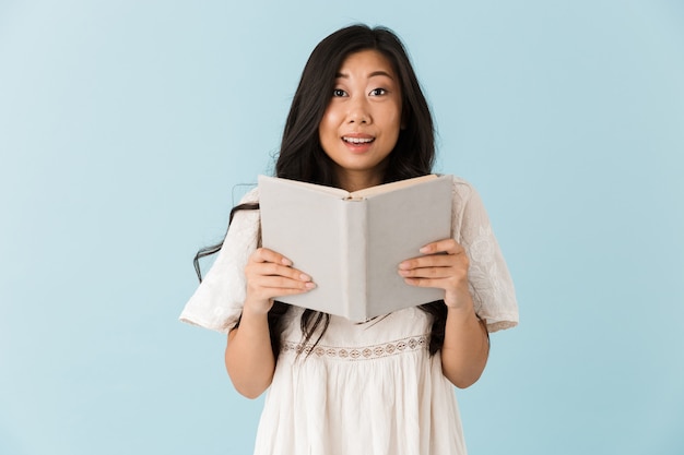 Belle femme asiatique isolée sur livre de lecture de mur bleu