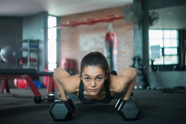 Belle femme asiatique jouer au fitness dans la salle de gymThaïlande fille a un corps minceTemps pour l'exerciceLes gens aiment la santéÉtirement du corps avant l'entraînementFemme sportive échauffement du corpspousser avec haltère