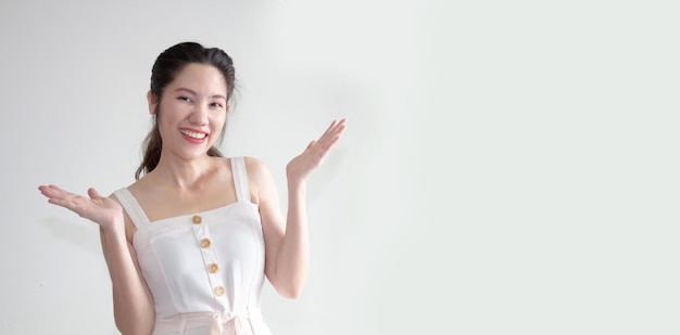 Une belle femme asiatique lève les deux paumes avec le sourire et est heureuse de montrer sa confiance sans souci