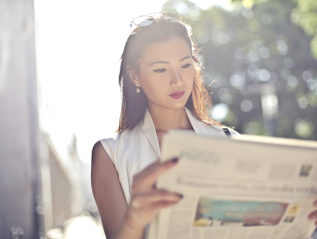 Belle femme asiatique lisant un journal