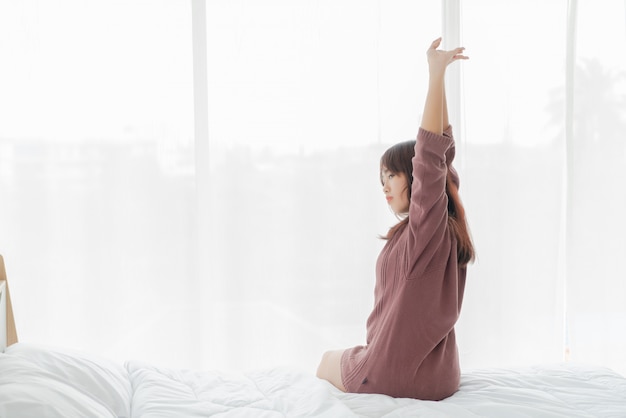 Belle femme asiatique sur le lit et se réveiller le matin