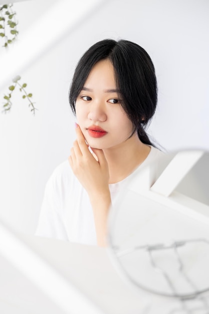 Belle femme asiatique matin soin du visage procédure de soins de la peau jolie dame posant avec miroir dans