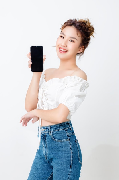 Belle femme asiatique à la mode montrant un téléphone mobile à affichage vierge sur fond blanc isolé et espace de copie Shopping paiement en ligne sourire bonne humeur