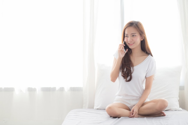 Belle femme asiatique parle de téléphone mobile intelligent