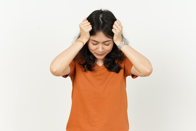 Belle femme asiatique portant un tshirt de couleur orange ayant des maux de tête isolé sur fond blanc