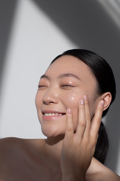 Belle femme asiatique posant avec de la crème pour le visage