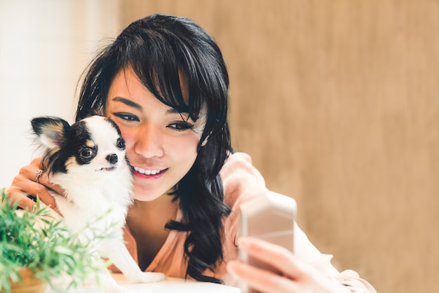 Belle femme asiatique prenant selfie avec mignon chien Chihuahua à la maison