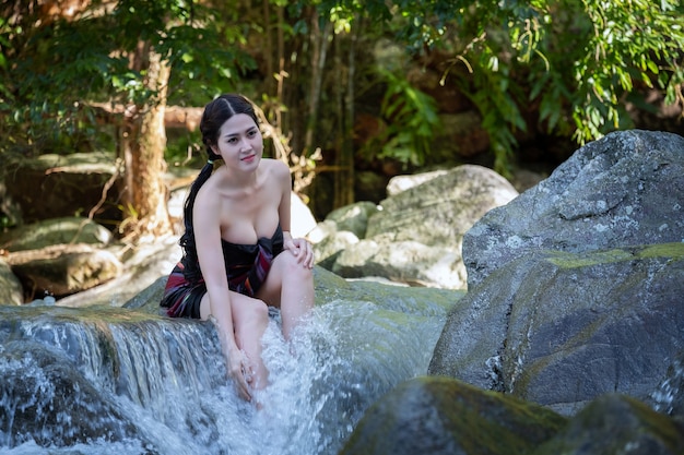 Belle femme asiatique avec une robe traditionnelle thaïlandaise explorer prendre une douche à la cascade