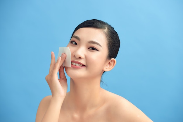 Belle femme asiatique séduisante utilisant un film propre à l'huile pour le visage pour éliminer l'huile sur le visage pour une peau fraîche du visage si fraîche et propre,