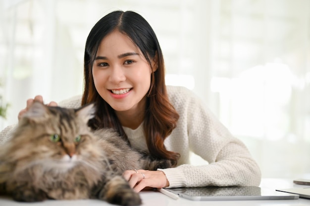 Belle femme asiatique avec son adorable chat persan dans son espace de travail à la maison