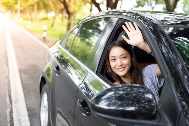 Belle femme asiatique, souriant et appréciant.driving une voiture sur route pour voyager