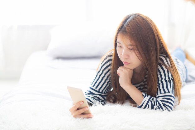 Belle femme asiatique souriante allongée se détendre sur le lit