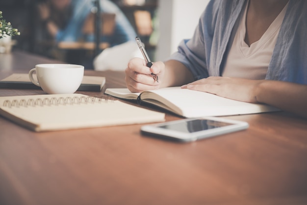 Belle femme asiatique souriante et écrit un cahier sur la table