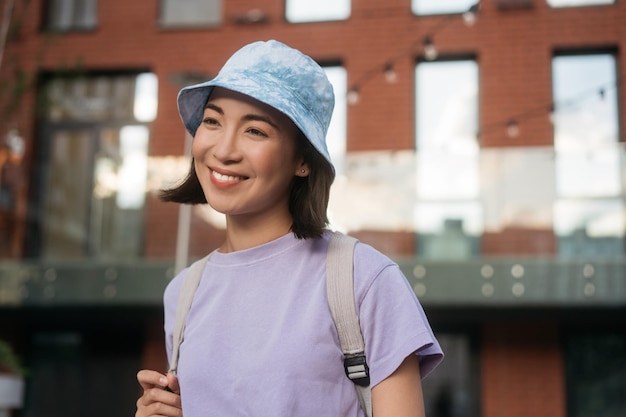 Belle femme asiatique souriante portant des vêtements décontractés, panama élégant marchant dans la rue