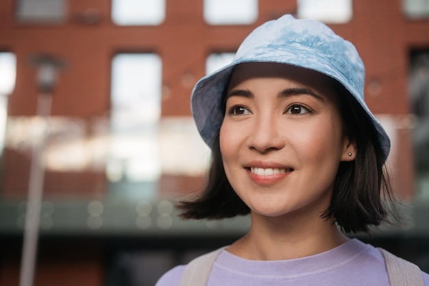 Belle femme asiatique souriante portant des vêtements décontractés, panama élégant regardant loin. Notion de voyage