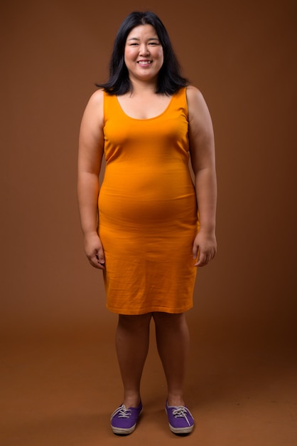 Belle femme asiatique en surpoids portant une robe sans manches orange