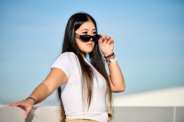 Une belle femme asiatique en T-shirt blanc et en short posant sur la jetée.