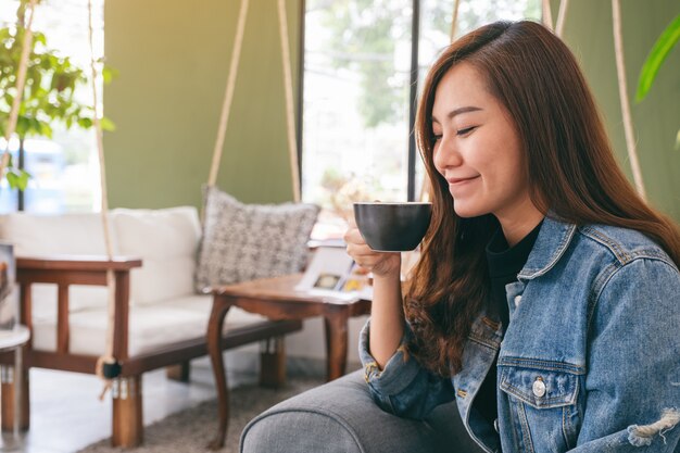 belle femme asiatique tenant et boire du café chaud au café